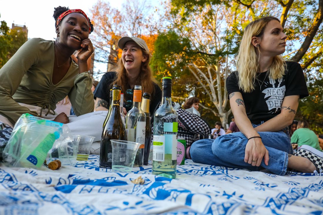 Young women sit in Washington Square Park with open bottles of wine